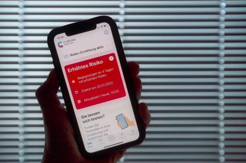 Hand holding smartphone with Corona warning APP