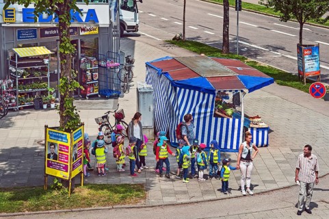 Fruit stand and kindergarten children with high visibility waistcoats