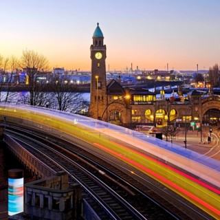 Atmospheric light trails of moving elevated railway and clock tower at sunrise