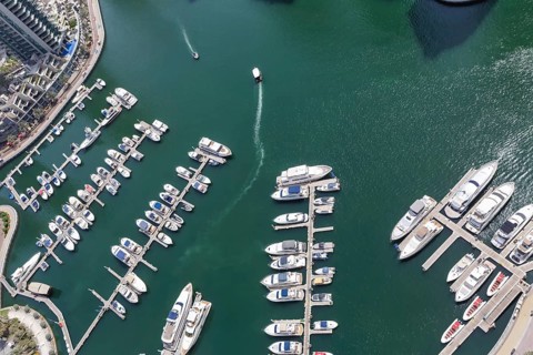 Dubai Marina and Harbour luxury wealth holiday with boats yacht from above in Dubai