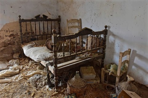 Wooden Marriage Bed with Chair and Wine Bottles in Baskets in Abandoned House