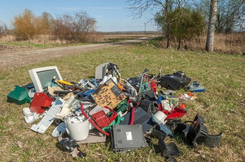 Polluting plastic waste and computer scrap illegally disposed of in a meadow
