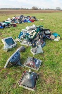 Polluting plastic waste and computer scrap illegally disposed of in a meadow