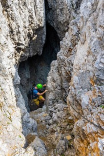 Young man climbing out of a rock hole