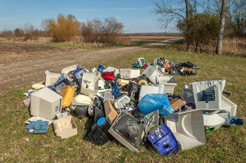 Polluting plastic waste and computer scrap illegally disposed of in a meadow