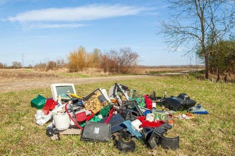Polluting plastic waste and computer scrap illegally disposed of in a meadow
