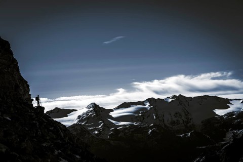 Climber on rocky outcrop with South Tyrolean mountains at blue hour
