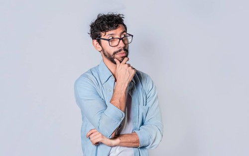Young man wondering with his hand on his chin on an isolated background