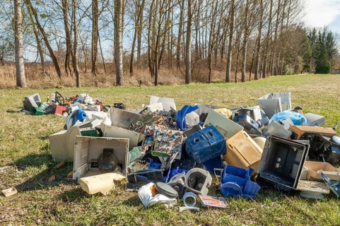 Polluting plastic waste and computer scrap illegally disposed of in a meadow