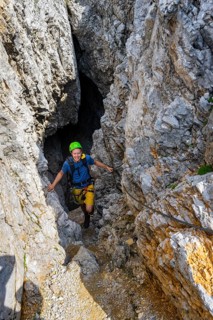 Young man climbing out of a rock hole