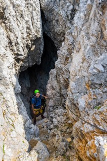 Young man climbing out of a rock hole