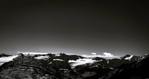 Climber on rocky outcrop with South Tyrolean mountains at blue hour