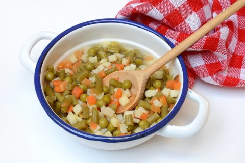 Ingredients for Russian salad in bowl and cooking spoon