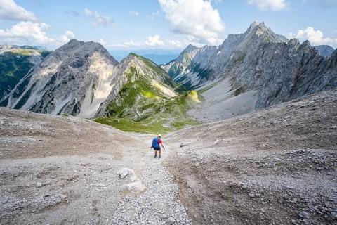 Hiker descends over a boulder field to the Lamsenjochhuette