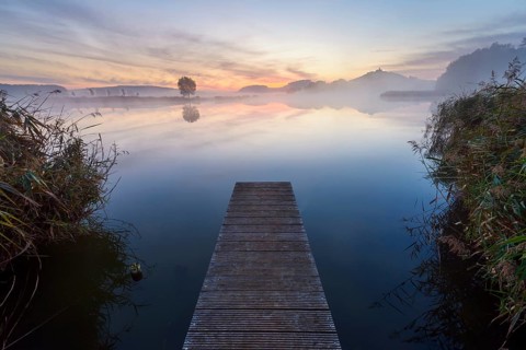 Wooden Jetty with Reflective Sky in Lake at Dawn