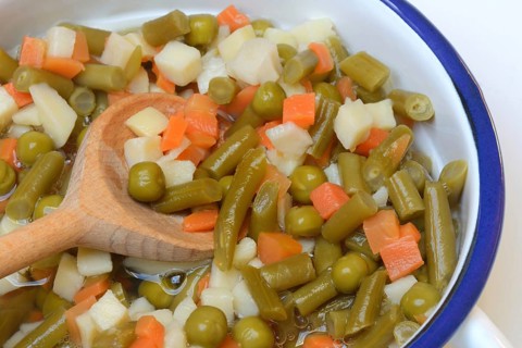 Ingredients for Russian salad in bowl and cooking spoon