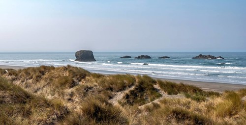 View over sandy beach with dunes and large rocks
