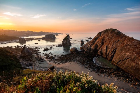 View of sea and sandy beach Harris Beach with rocks at sunrise