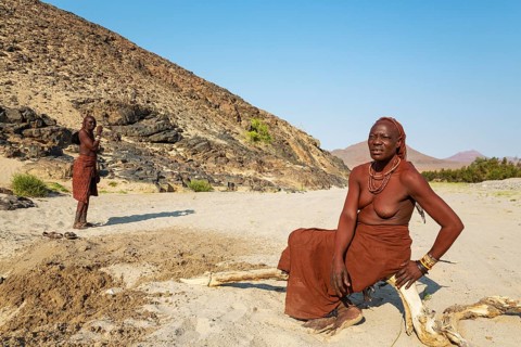 Himba women at the bank of the dry river bed of the Hoarusib river