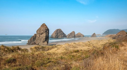 View over sandy beach with dunes and large rocks
