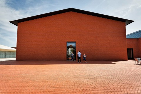 Visitors in front of building made of red bricks in the shape of a warehouse