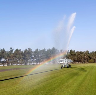 Irrigator machine spraying water turf farming