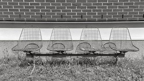 Four wire chairs in front of a wall