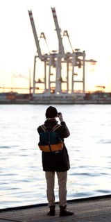 A person takes pictures of loading cranes at the Norderelbe in Altona