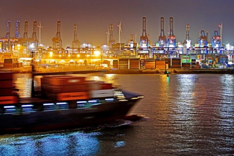 Container ship on the Norderelbe in front of loading cranes at the container terminal Burchardkai at night