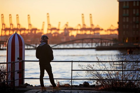 A person in front of loading cranes at the Norderelbe in Altona