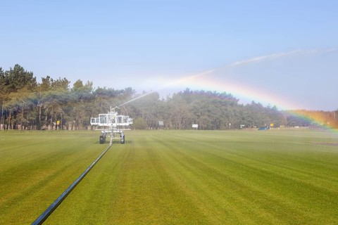Irrigator machine spraying water turf farming
