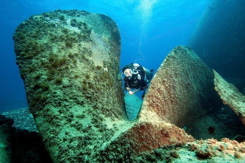 Diver looks down on giant propeller from sunken shipwreck Astron
