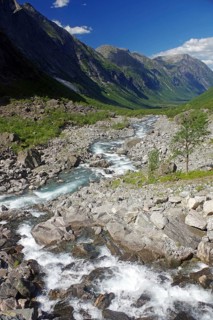 Wild stream in a narrow valley framed by mountains