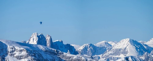 Hot air balloons flying over snow-covered Alpine peaks