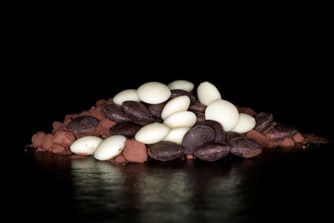Dark and white couverture chocolate drops lying on cocoa powder