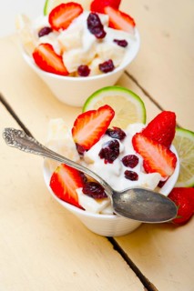Fruit and yogurt salad healthy breakfast over white wood table