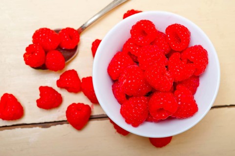 Bunch of fresh raspberry on a bowl and white wood rustic table