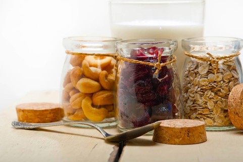 Healthy breakfast ingredients milk oat cashew nuts dried cramberry craisinns