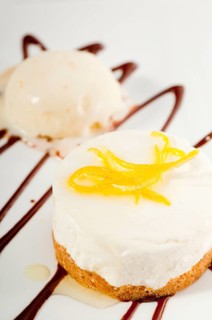 Very elegant lemon mousse dessert served whith lemon peel on top and vanilla ice cream on side