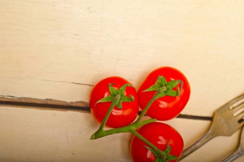 Ripe cherry tomatoes cluster over white rustic wood table