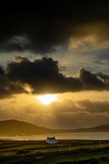 Small house on the sea coast in the backlight at golden hour
