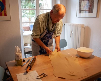 Man rolling out strudel dough at a table