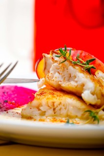 Sea bream orata fillet butter pan fried with fresh peach prune and dragonfruit slices thyme on top