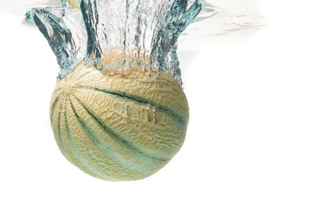 Cantaloupe melon splash and sinking isolated against white background