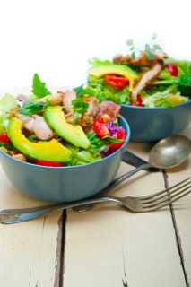 Fresh and healthy Chicken Avocado salad over rustic wood table
