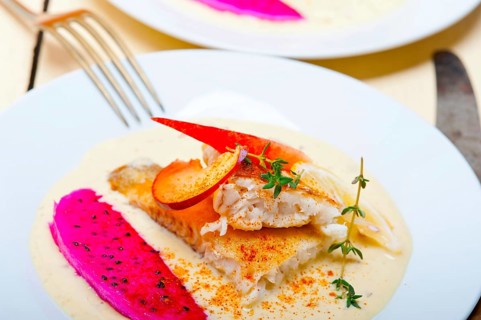 Sea bream orata fillet butter pan fried with fresh peach prune and dragonfruit slices thyme on top