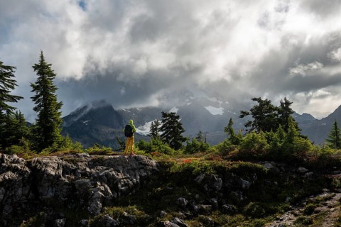 Hiker in front of cloudy Mt. Shuksan with snow and glacier