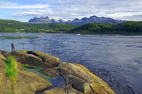 Angler standing on the bank of a fast flowing water