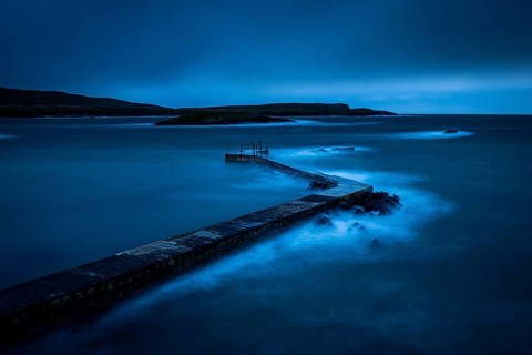 Sea surf on concrete jetty at blue hour
