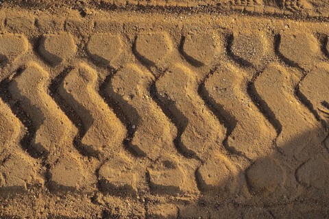 Wide tyre print in the sand from agricultural machine